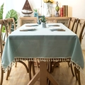 Close-up of light green linen-style tablecloth featuring elegant white cotton tassels - 140x180 / Tassel Style / Teal