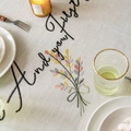Embroidered floral linen tablecloth with elegant black cursive script and tassels - 140x140 / Pink Gray Yellow Flowers with Tassels