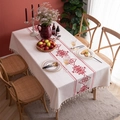 Gros plan d'une nappe en lin de coton crème avec broderie florale rouge et bordure à glands - 140x180cm / Nuage de Chance Rouge Brodé Avec Glands