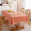 Bohemian orange and white herringbone tablecloth with fringe tassels on a wooden dining table - 60x60cm / Orange Wave With Tassels