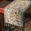Runner da tavola jacquard con motivi floreali blu e bordo con nappe su tavolo in legno - 35x120 / Stile camelia blu (con nappe blu)