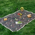 Detail showing vintage floral pattern cotton tablecloth with white fringe on grass - Black Floral + Dense Tassels