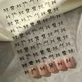 Detail van zwarte strik nagelstickers op roze nagels tegen een zijden achtergrond - Zwart Plat (YT487-1)