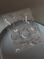 Macro shot of dark-style nail art stickers with bone and ribbon patterns on a ceramic plate - Silver Spine Skeleton (YT6115Si)