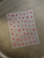 Detailed macro shot of red star nail stickers featuring sparkling clear rhinestones - Red