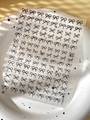 Close-up of black bow embossed nail art stickers on a white textured plate with soft shadows - Black (YT5605)