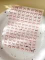 Detail view of YT5608 minimalist red bow nail art stickers on a decorative white plate - Red (YT5608)