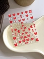 Detail of 3D embossed heart and bow nail art stickers on a white ceramic tray - Relief YT4209 (Red White Heart Candy)