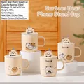 Creamy ceramic cartoon bear mug with matching lid and built-in mobile phone holder stand - Bear Stand Mug