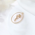 Dettaglio macro del ciondolo ovale in madreperla bianca con una rosa placcata oro 14K - Giugno