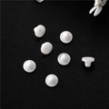 Macro shot of seven white silicone earring backs on black leather texture - White Disc Style (D1683)