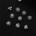 Detailed view of clear silicone earring backings on a textured black leather surface - Transparent Bullet Style (D1685)