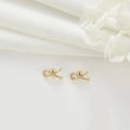 Detail of 14k gold-plated bow earrings set with white cubic zirconia on white linen - Rhinestone Bow Knot Style (H-7598)