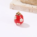 Macro detail of red enamel Easter egg pendant with white flowers and crystal accents - Red