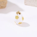 Macro detail of white enamel Easter egg pendant with yellow floral design and gold ring - White