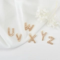 Detail van 14K vergulde zirkonia letterhangers U-Z op witte zijden achtergrond - Letter U / Goud
