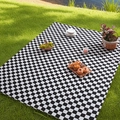 Classic black and white checkerboard picnic mat spread on a lush green grass field - Standard Size / Black and White Plaid