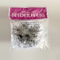 Detail eines dehnbaren Spinnennetzes mit Kunststoff-Spinnen in Verkaufsverpackung - Weiße Baumwollnetz Und Kleine Spinnen (Groß)