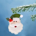 Ciondolo di Babbo Natale in feltro con cappello verde su un ramo di pino innevato - Babbo Natale con Cappello Verde