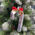 Nahaufnahme von Disco-Zuckerstangen-Anhänger mit roter Schleife an einem grünen Weihnachtsbaum - Roter Schleifen-Stil / Silber