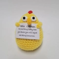 Detailaufnahme eines handgehäkelten gelben Kükens mit einer inspirierenden Infokarte - Huhn