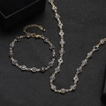 Gold evil eye jewelry set featuring a necklace and bracelet on a black textured surface - Black and White Evil Eye Necklace and Bracelet Set (6)