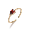 Detalle de anillo dorado con textura de cuentas y circonita roja en forma de pera engastada - Rojo