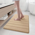 Dettaglio del tappetino da bagno a righe in pile corallo kaki con trama morbida e assorbente - 40x60cm / Cammello