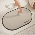 Detail of oval anti-slip bath mat in beige with BATHING text and absorbent texture - Minimalist Oval-8