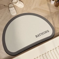 Detail view of semi-circular diatom mud bath mat with BATHING text on wood floor - Mushroom Round Style / Agarwood / 40x60cm