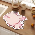 Detailed view of pink pig-shaped diatom mud absorbent mat on a wooden kitchen countertop - Pig