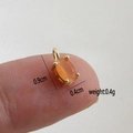 Detail shot of mini orange cat eye stone pendant in gold setting on finger for scale - Orange Oval Cat's Eye Stone Pendant