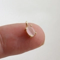 Macro view of mini pink zircon pendant with 18k gold plating held by fingers - Pink Oval Cat's Eye Stone Pendant