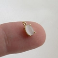 Macro detail of a 18k gold plated mini pendant with an oval gemstone held on fingertips - Off-White Oval Cat's Eye Stone Pendant