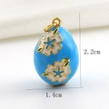 Macro detail of blue enamel egg pendant with white flower patterns and 18k gold plating - Sky Blue Floral Style