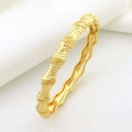 Detailopname van de golvende gouden armband met een gelaagd bamboe-stijl getextureerd design - Bamboe Golf Stijl / Goudgeel