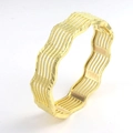 Detail van een goudkleurige holle armband met vintage golfkanten en geweven patroon - Goud