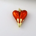 Macro view of a vibrant translucent orange heart pendant with gold liquid metal base - Orange Red