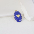 Nahaufnahme des ovalen blauen Emaille-Anhängers mit Goldherz und Zirkon-Umrandung - Dunkelblauer Hintergrund Mit Strass Stil (H)