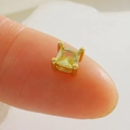 Vue macro d'un petit zircon carré jaune sur monture dorée à 4 griffes tenue par un doigt - Strass Carré Jaune Clair-Or (14)