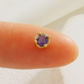 Macro shot of a tiny gold four-prong stud earring with a purple round-cut crystal on a fingertip - Purple Round Rhinestone-Gold (01)