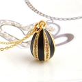Macro view of a gold-plated vintage egg pendant with black enamel and white zircon inlay - Black
