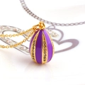 Macro detail of purple enamel easter egg pendant with gold stripes and zircon inlay - Purple