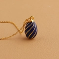 Detailed close-up of blue enamel egg pendant with gold spiral texture and fine chain - Blue