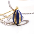 Macro shot of blue enamel egg pendant necklace with gold chain and zircon inlay details - Dark Blue