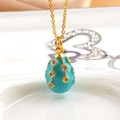 Macro view of blue enamel egg pendant with gold geometric diamond-set patterns - Emerald