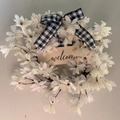 Artificial white dogwood wreath with black and white buffalo plaid bow and welcome sign - White