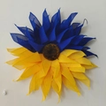 Detailstruktur des Sonnenblumenkranzes mit blauem und gelbem Netzgewebe auf weißer Wand - Sonnenblumen-Kranz