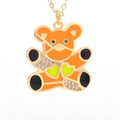 Detail of a golden bear pendant with orange enamel, green hearts, and micro zircons - Orange