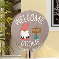 Round wooden garden welcome sign featuring a gnome in a red hat on a metal stand - Grey Background Faceless Gnome Door Plaque